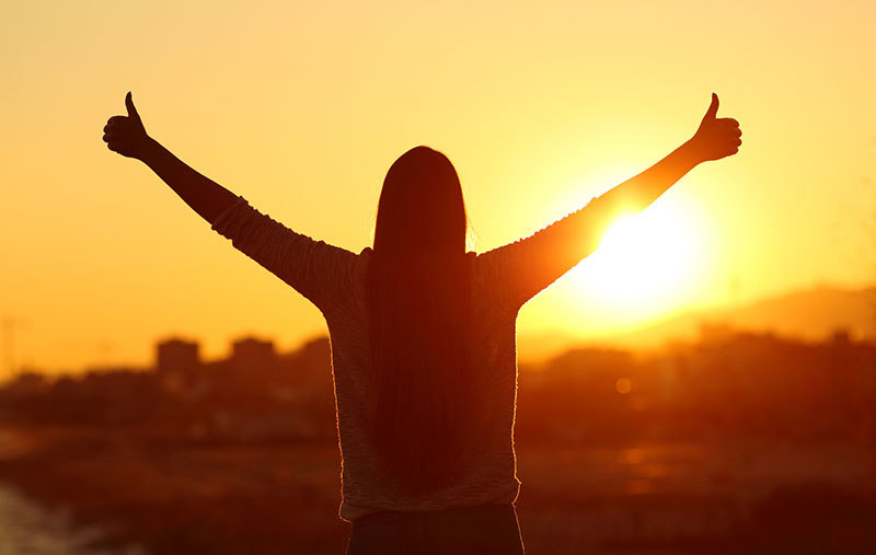 Quantum Services Benefits Woman giving thumbs up while looking at sunrise